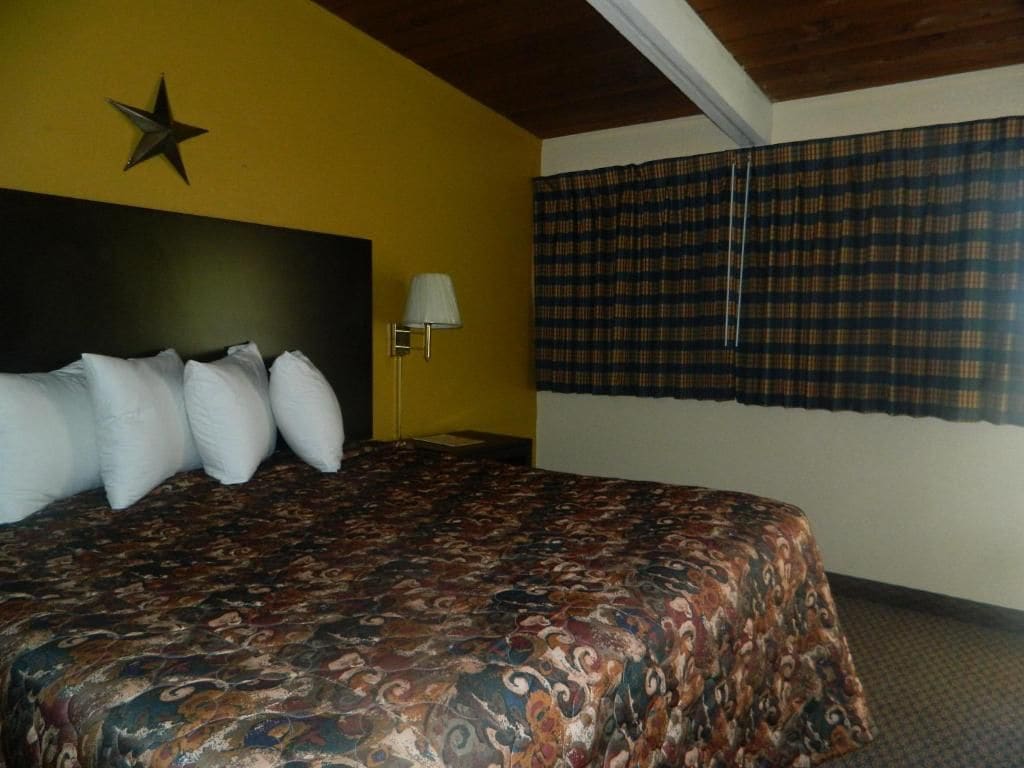 Une chambre d’hôtel avec un grand lit, une décoration en forme d’étoile au mur, une lampe et des rideaux à carreaux.