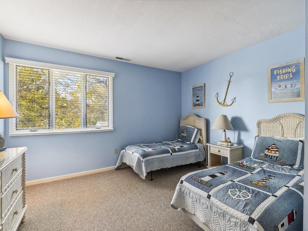 Een slaapkamer met twee bedden, een kaptafel, een raam met zonwering en decoratie met een nautisch thema.