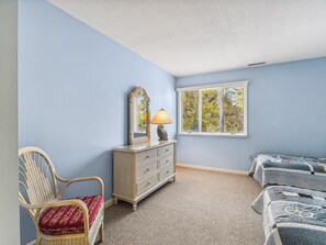 A bedroom with a single bed, a dresser, a chair, and a window with blinds. - 2-Bedroom Condo w/ Private Deck near Bethany Beach (Bethany Beach)