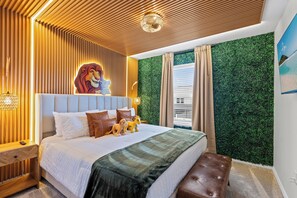 Ein Schlafzimmer mit Bett, Kopfstütze, Nachttisch, Wandlampe, einer gemütlichen Couch, einer grünen Wand und einem Fenster mit Vorhängen.