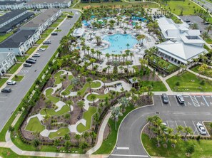 Eine Vogelperspektive zeigt ein Resort mit einem zentralen Schwimmbecken, angelegten Gärten und einem Parkplatz.