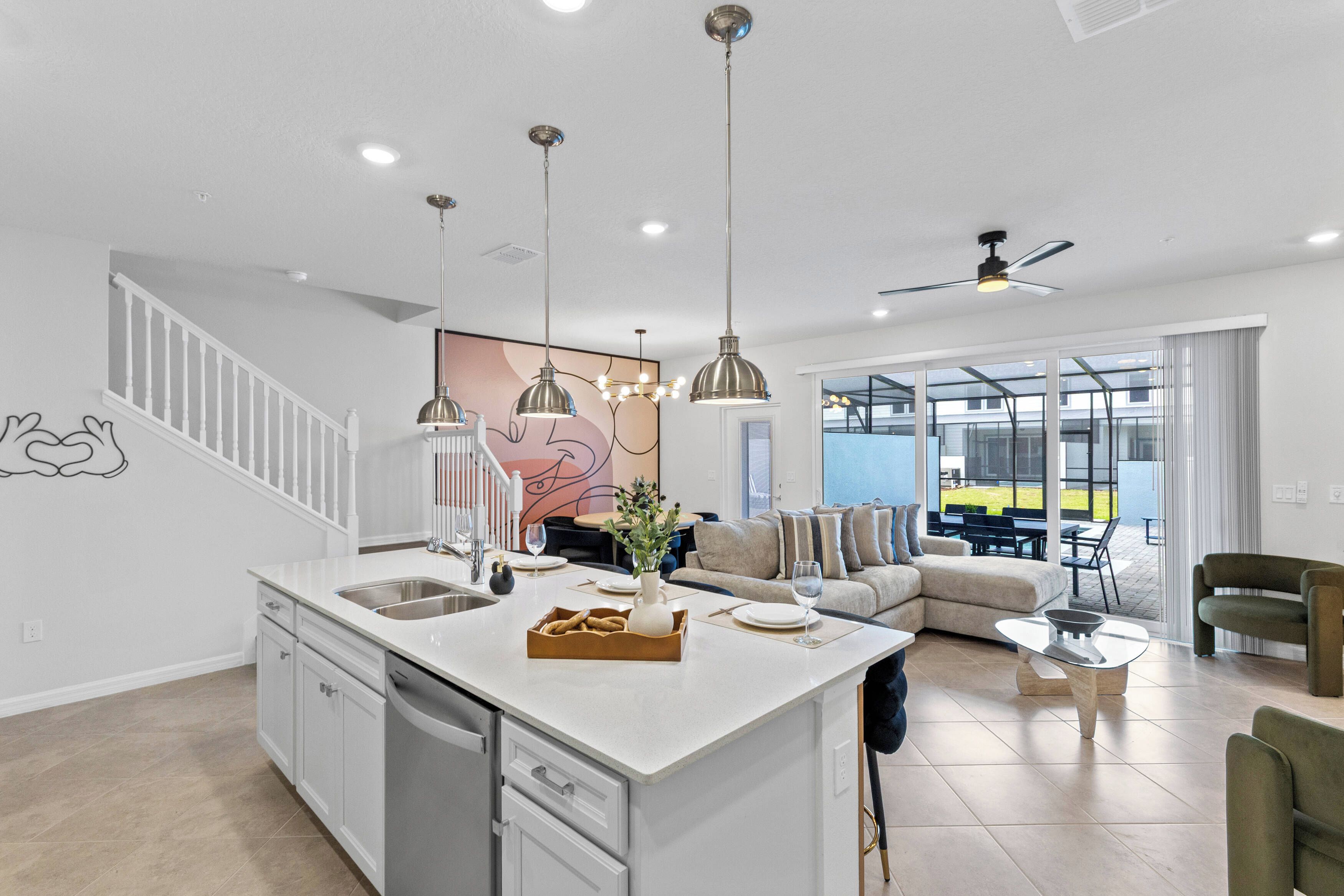 A modern kitchen with a central island, dining area with a sofa, and a view to the outside.