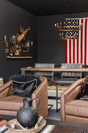 Ein modernes Wohnzimmer mit Ledersofas, einer Kronleuchter und einer amerikanischen Flagge.