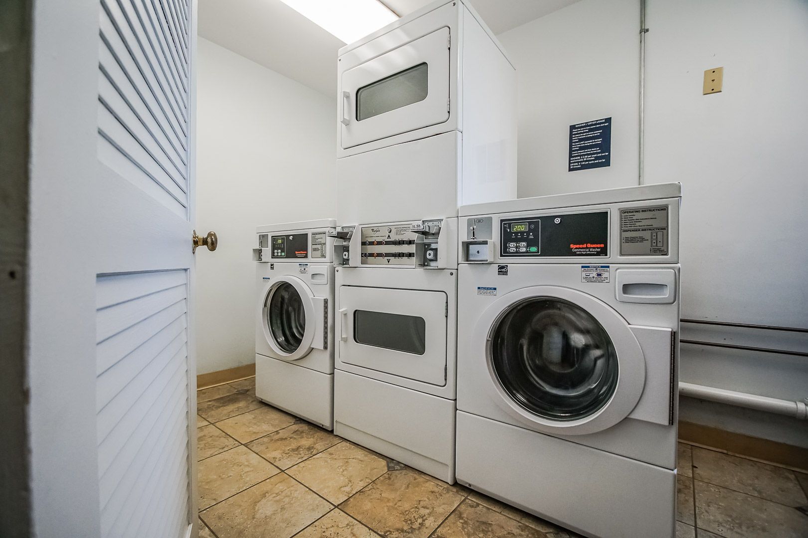 A laundry room with three stacked washers and dryers, a control panel, and a sign with operating instructions.