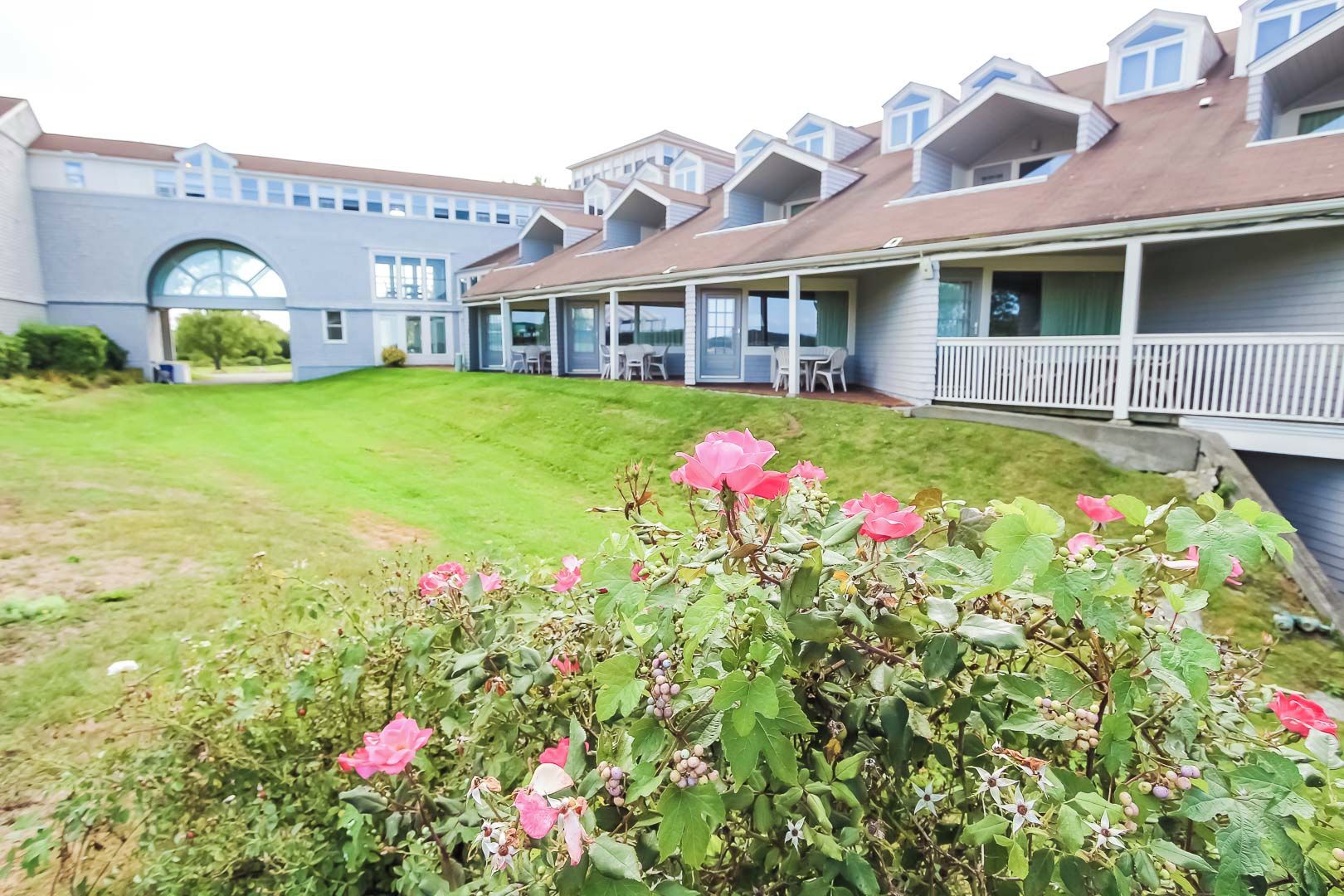 A residential building with multiple balconies, a well-maintained lawn, and flowering plants in the foreground.