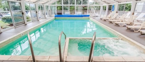 Ein Hallenbad mit klarem Wasser, einer blauen Liegefläche und Liegestühlen entlang der Seiten.