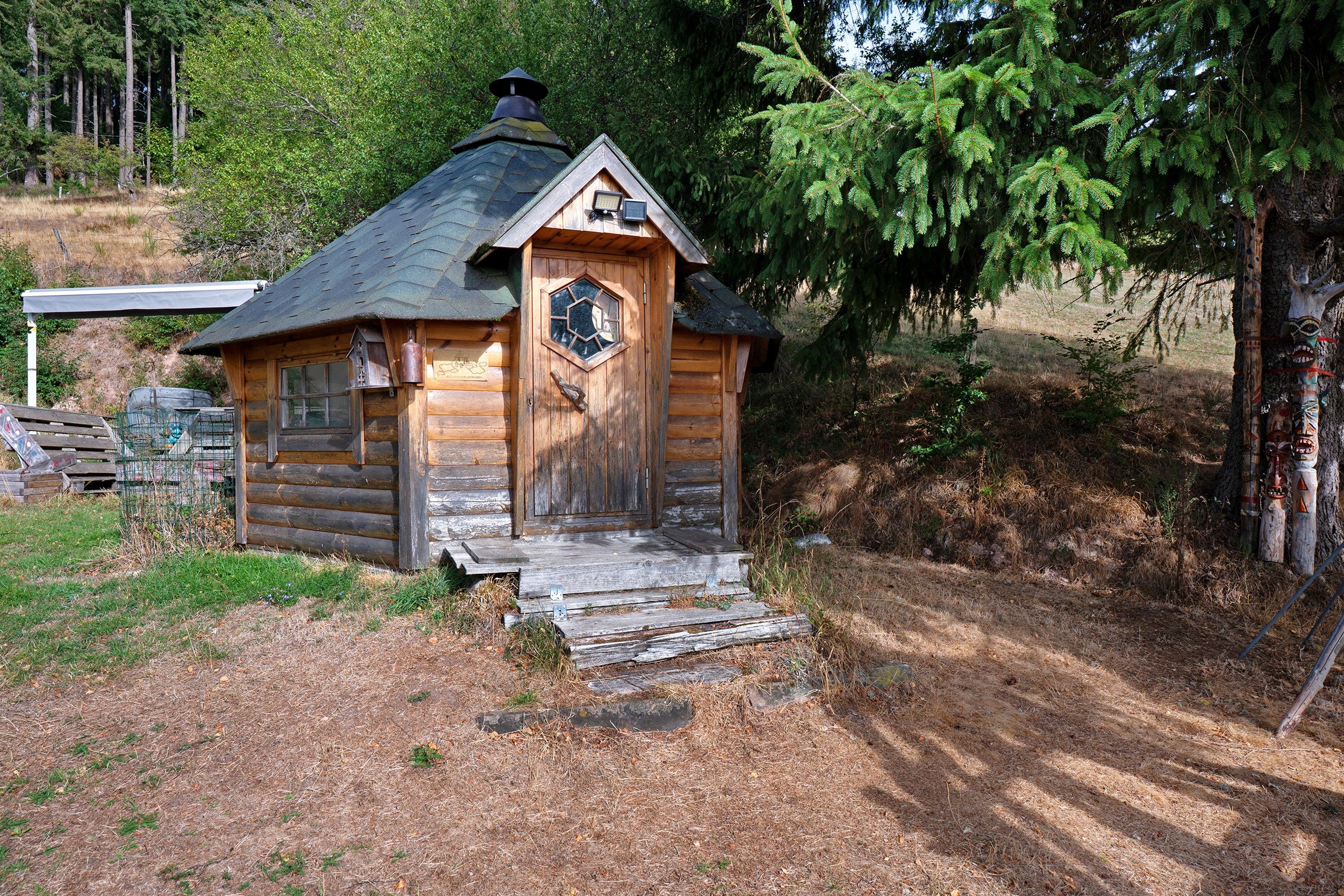 A small wooden cabin with a hexagonal door, a chimney, and a small porch.