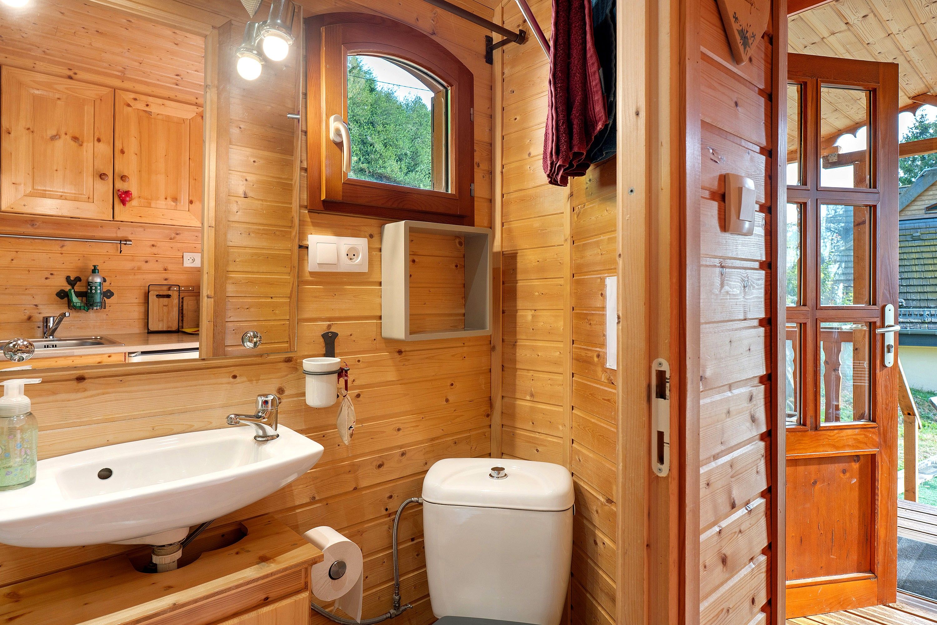 Baño de cabaña de madera con lavabo, inodoro y ventana.