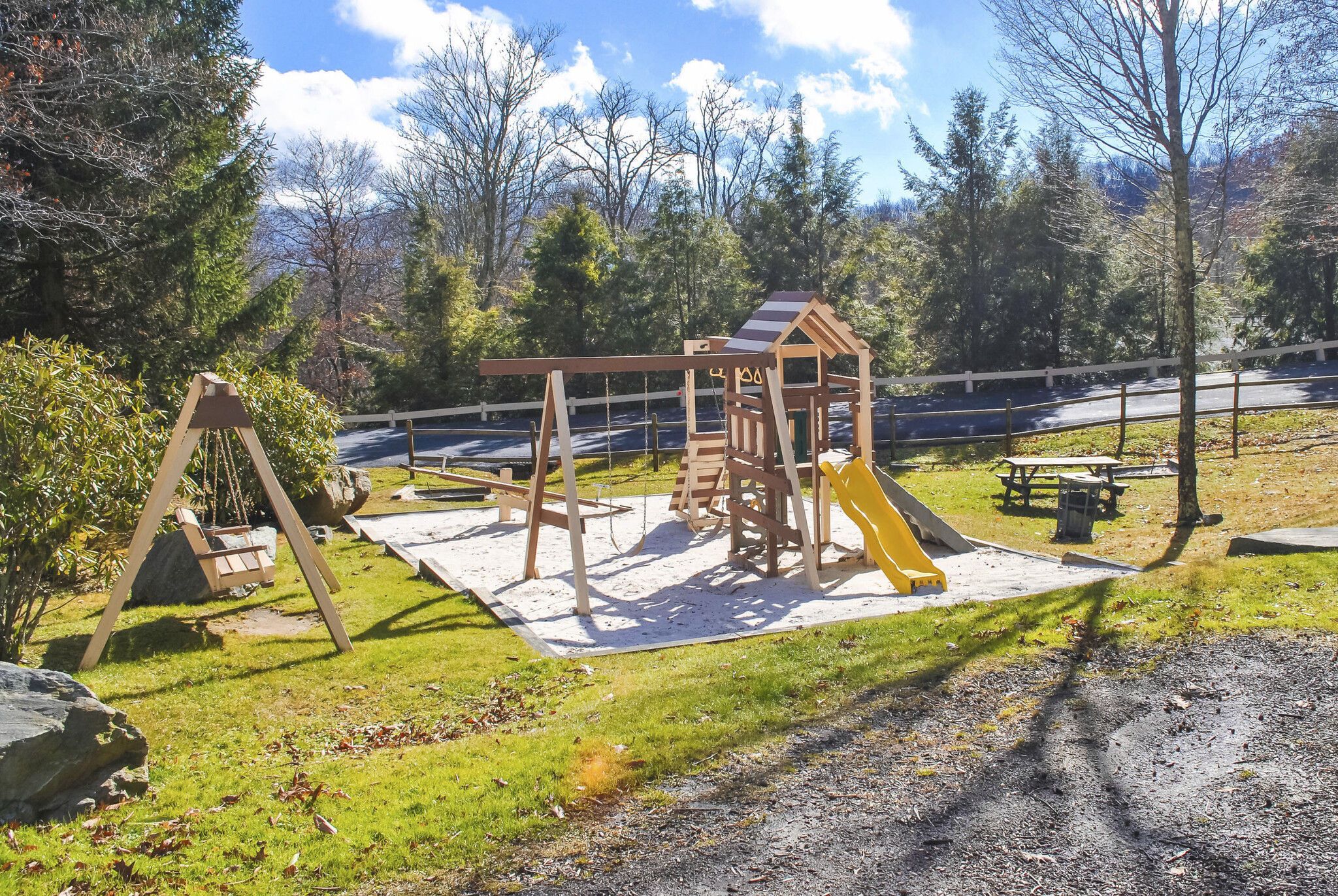 Une aire de jeux avec des balançoires, une structure d’escalade et un toboggan.