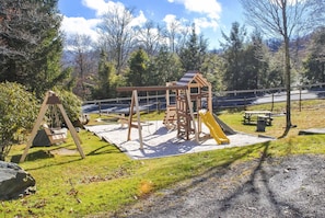 Une aire de jeux avec des balançoires, une structure d’escalade et un toboggan.