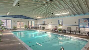 Une piscine intérieure avec des couloirs clairement délimités, des chaises longues et une signalisation de sécurité.
