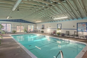 Une piscine intérieure avec des couloirs clairement délimités, des chaises longues et une signalisation de sécurité.