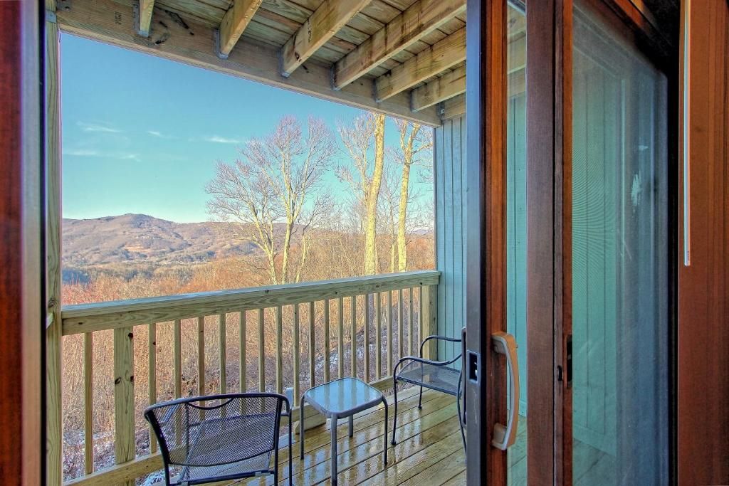 A wooden deck with a glass door leading to a balcony overlooking a mountainous landscape.