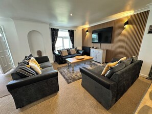 Ein modernes Wohnzimmer mit einer Sofagarnitur, einem Couchtisch, einem Fernseher und einem Schrank.