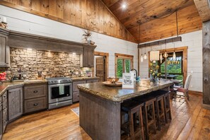 A spacious kitchen with a large island, wooden cabinets, and a stone backsplash. - Hot Tub, Mountain Views, Games & Outdoor Living (Epworth)