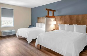 A hotel room with two beds, a wooden headboard, a window with a view, and a heater. - Extended Stay America Premier Suites - Laredo - North (Laredo)