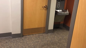 Un pasillo con alfombra, una puerta de madera y un dispensador de agua.