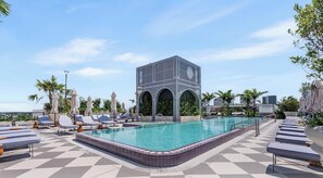 Ein Poolbereich mit Liegestühlen und einem modernen Gebäudebau.