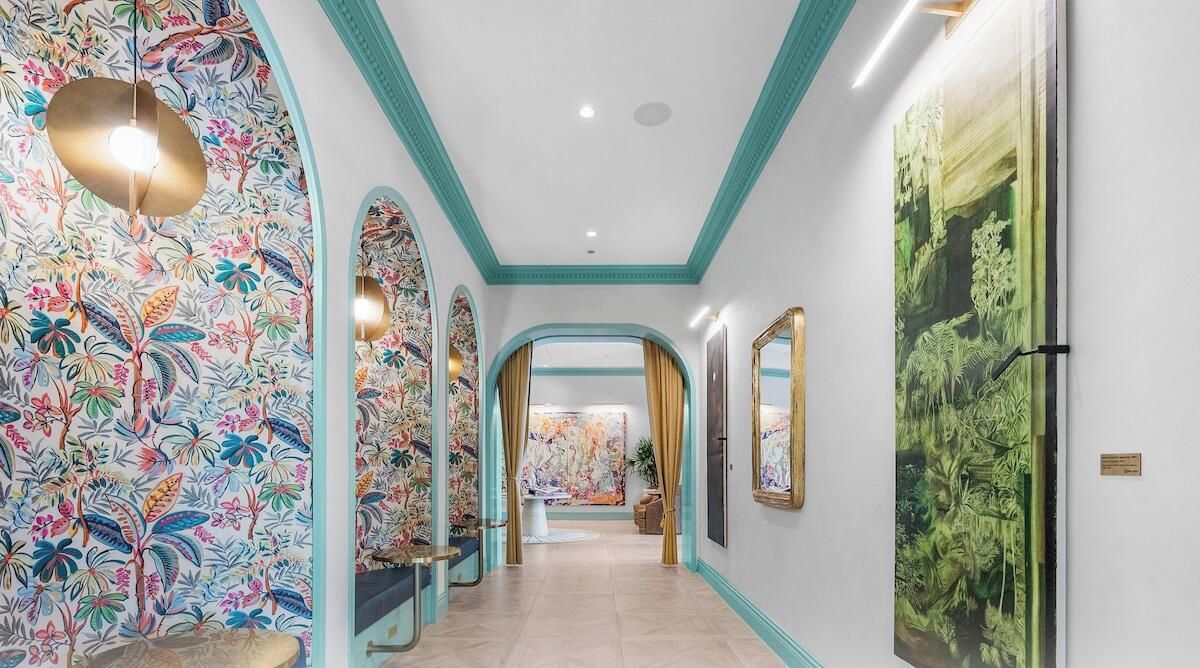 A hallway with floral wallpaper, a ceiling light, and a large painting on the wall.