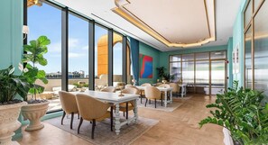 Un espace de restauration moderne doté de grandes fenêtres, offrant une vue sur le paysage urbain, et présentant un design intérieur contemporain.