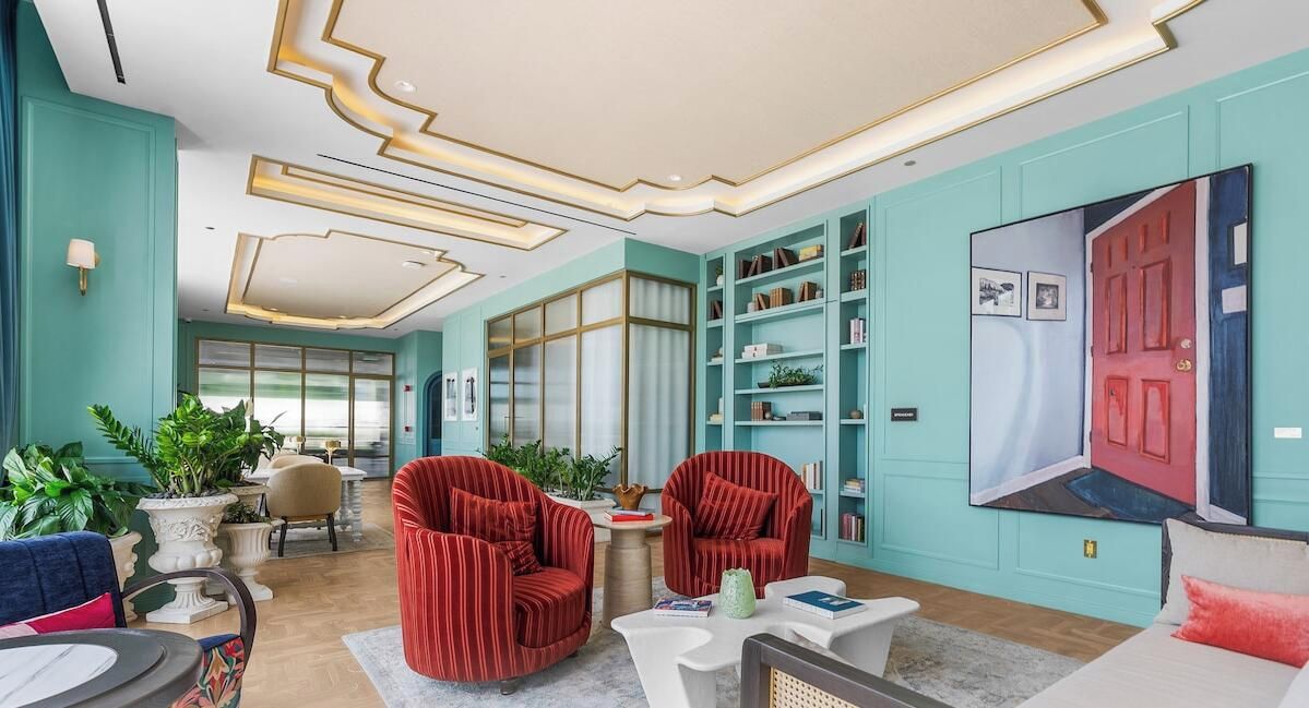 Un salon moderne avec des murs de couleur turquoise, des fauteuils à rayures rouges et une bibliothèque.