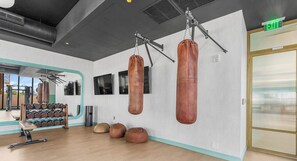 A gym with punching bags, a bench, and a mirror. - Nomad Residences Wynwood Art, Pool & Miami Nights (Miami)