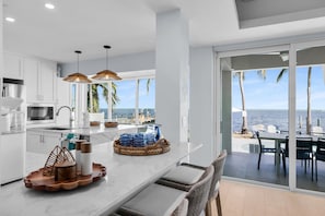 A modern kitchen with a large island, white cabinetry, and a view of the ocean. - Gulfstream Paradise Open Water on the Gulf  6 bed 4 bath with pool, 4 kayaks, and dockage (Marathon)