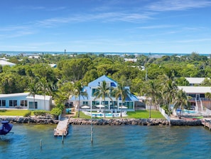 A modern house with a pool, surrounded by lush greenery and a clear view of the ocean. - Gulfstream Paradise Open Water on the Gulf  6 bed 4 bath with pool, 4 kayaks, and dockage (Marathon)