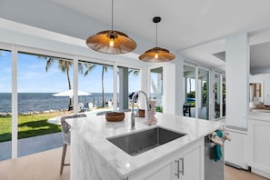 A modern kitchen with a large island, white cabinetry, and a view of the ocean. - Gulfstream Paradise Open Water on the Gulf  6 bed 4 bath with pool, 4 kayaks, and dockage (Marathon)