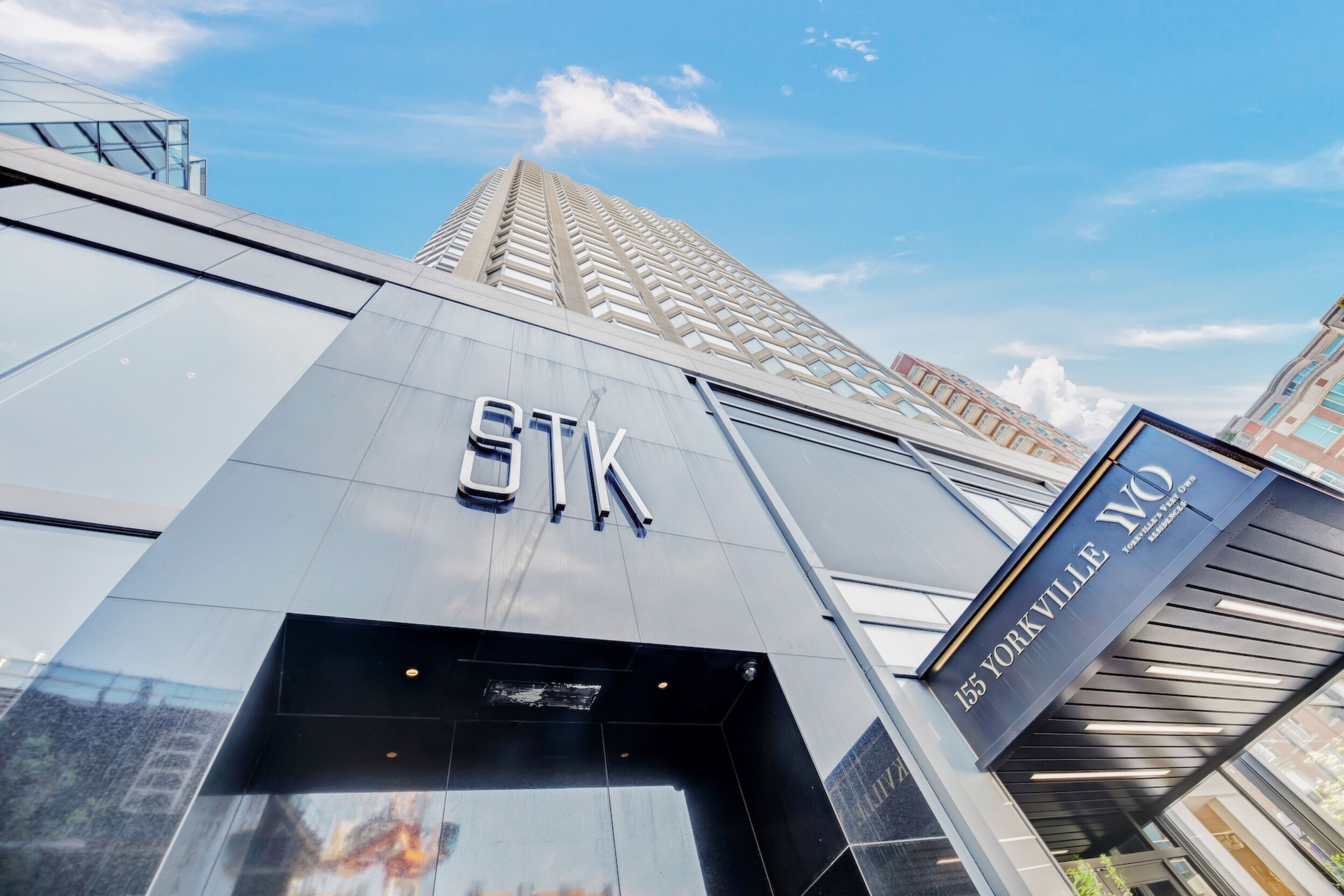 Een modern gebouw met het bord 'STK' en '155 YORKVILLE' dat het adres aangeeft.