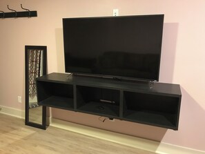 A flat-screen TV mounted on a black entertainment center with a mirror and a power outlet on the wall. - Walk to everything! This apartment puts you in the heart of historic Galena! (Galena)
