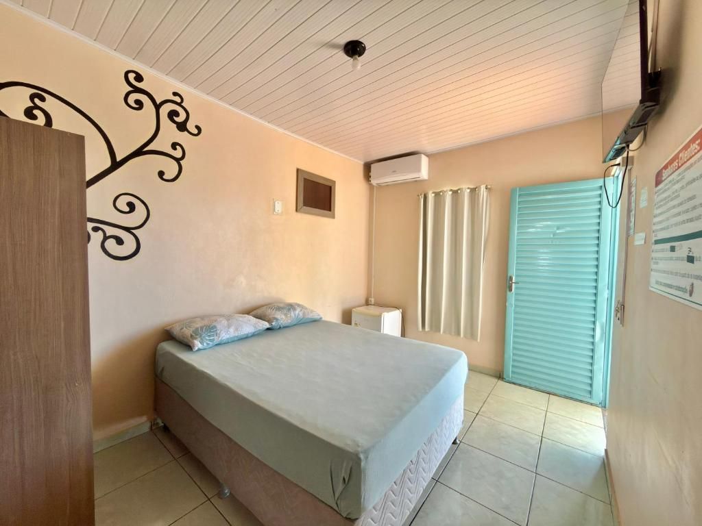 A bedroom with a bed, a wardrobe, a window with curtains, and a door.