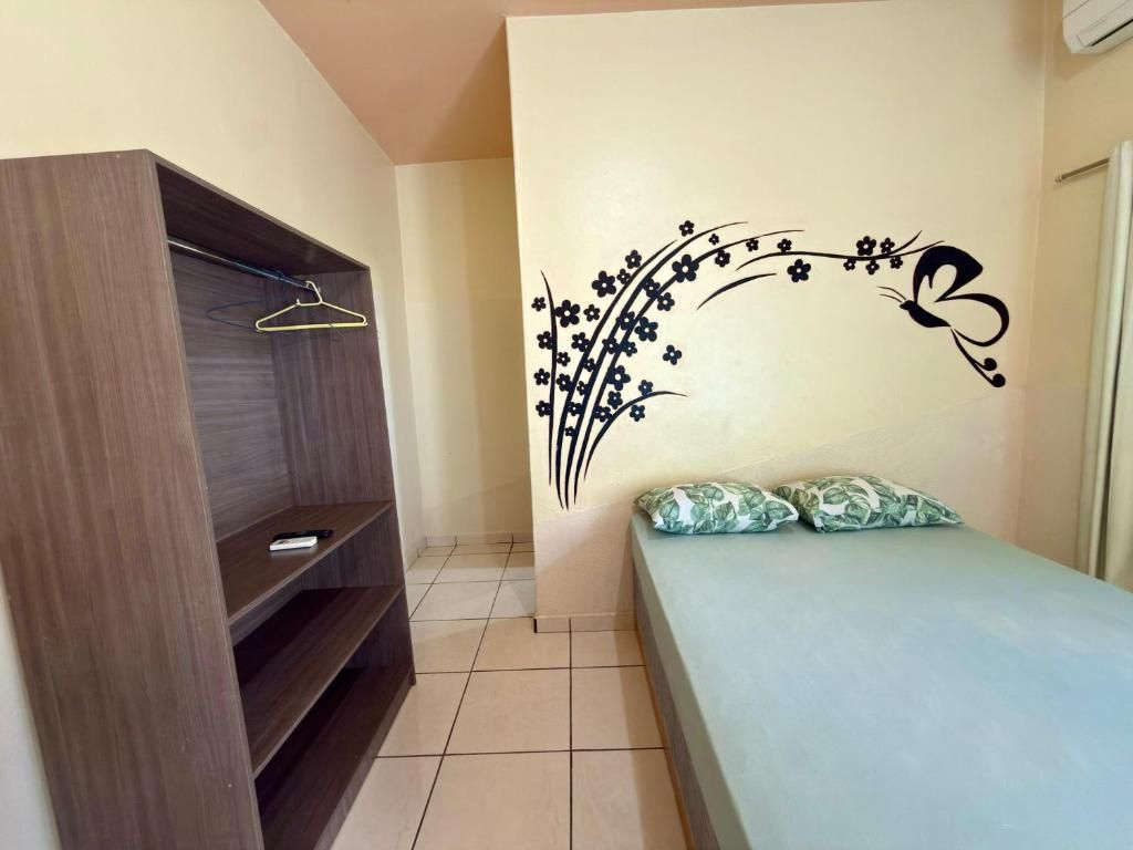 A bedroom with a bed, a wardrobe, and a wall decoration.