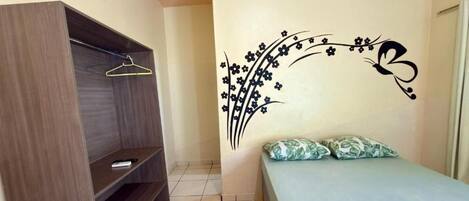 A bedroom with a bed, a wardrobe, and a wall decoration.