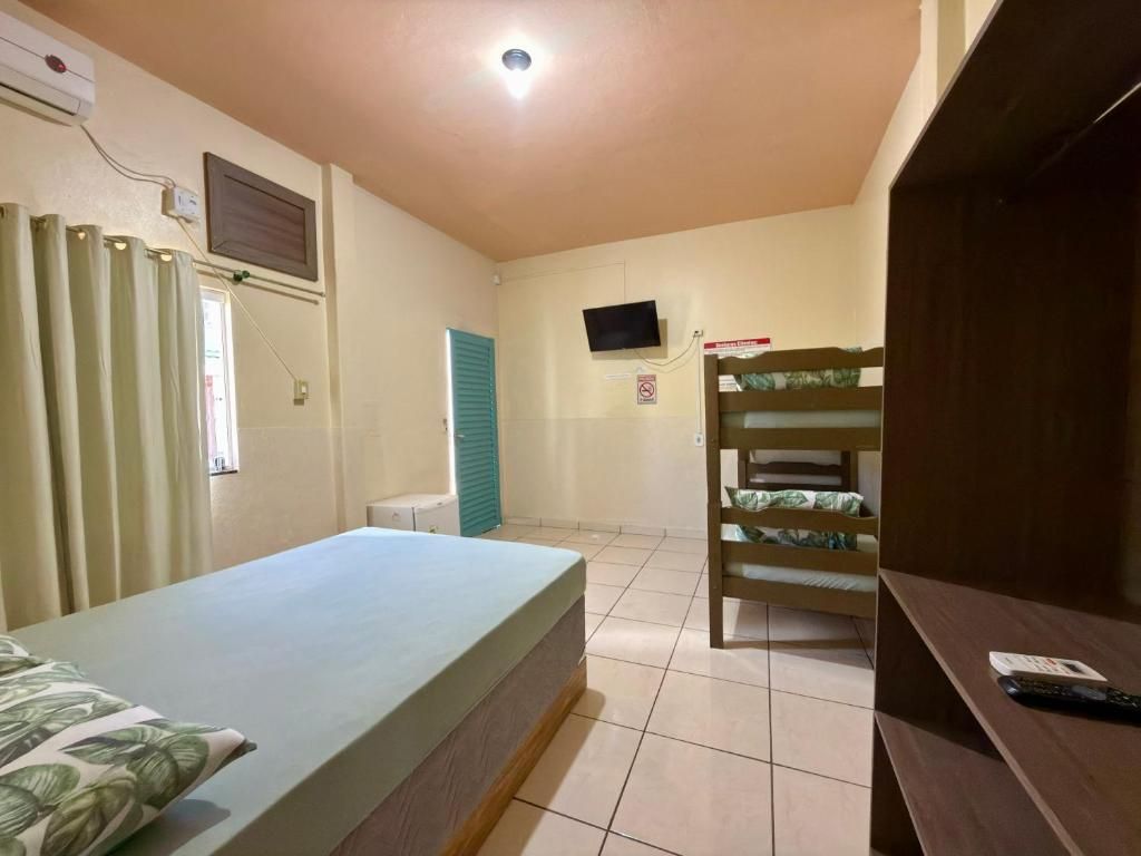 Quarto com cama, televisão, beliche e escrivaninha.
