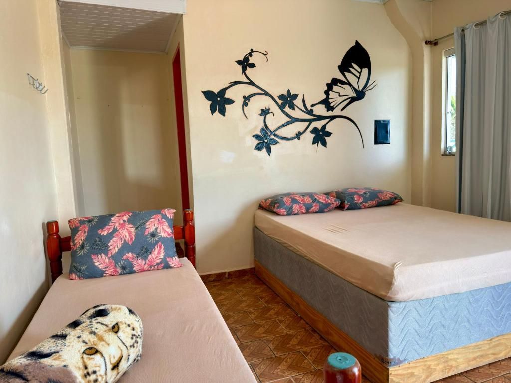 Une chambre avec deux lits, une décoration murale à motifs floraux et une fenêtre avec des rideaux.