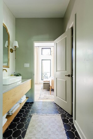 A hallway with a white door, a mirror, and a sink with a wooden countertop. - The Pine at Dunlap Ridge (Laurel Township)