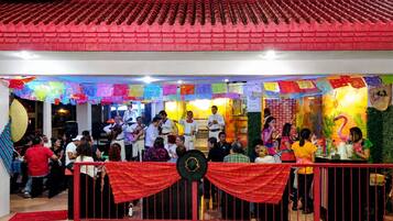 A restaurant with a red tiled roof, colorful decorations, and a group of people dining.
