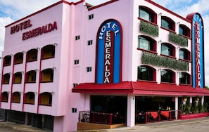 A pink and red hotel with multiple balconies and a sign reading 'Hotel Esmeralda'.