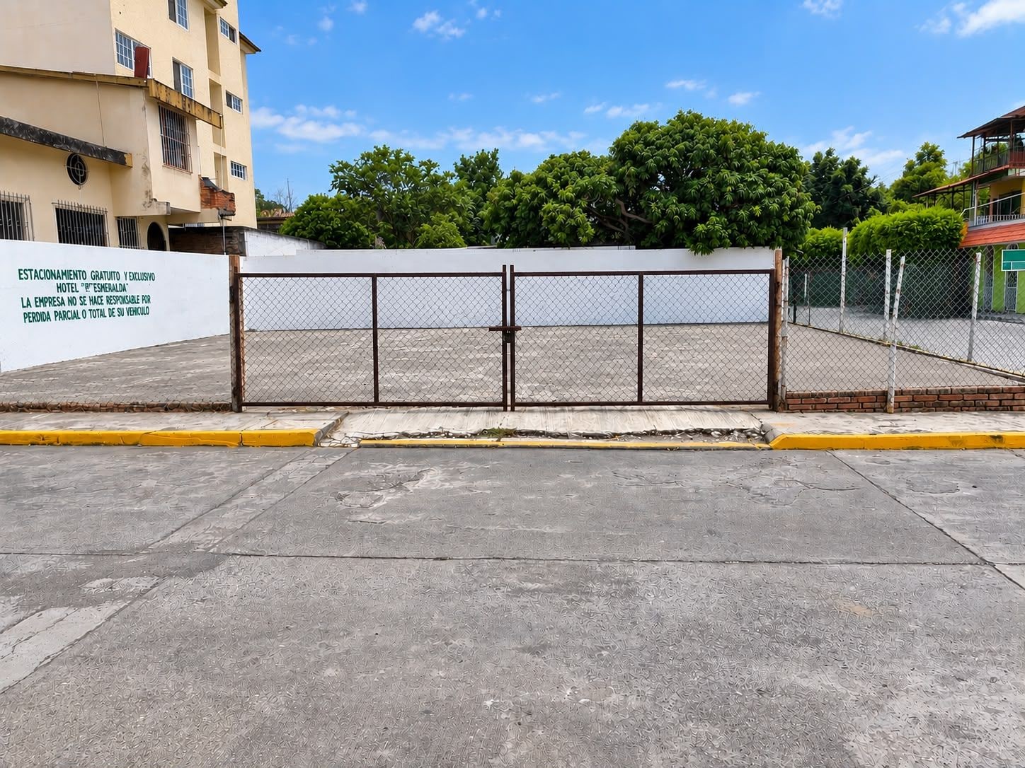 Un estacionamiento vallado con un letrero blanco que indica estacionamiento gratuito y exclusivo.