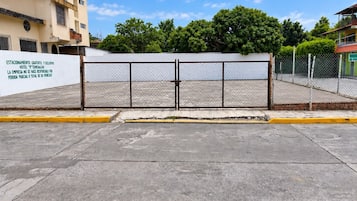 Un estacionamiento vallado con un letrero blanco que indica estacionamiento gratuito y exclusivo.