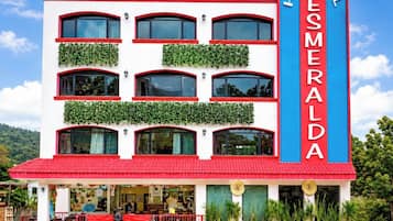 Un hotel con fachada roja y blanca, múltiples ventanas y un letrero llamativo.