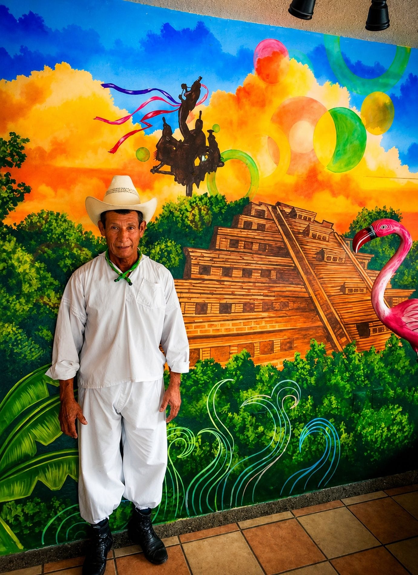 A person standing in front of a mural with a pyramid, a flamingo, and a horse.