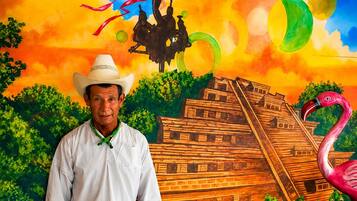 A person standing in front of a mural with a pyramid, a flamingo, and a horse.