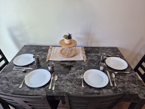 A dining table set with plates, cutlery, and a small potted plant. - Newly Built 2-bedroom apartment in Defiance with AC, In-unit Laundry and monitor (Defiance)
