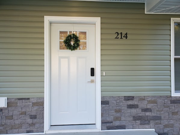 A house with a white front door, a stone wall, and the number 214 on the siding.