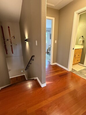 A staircase with a handrail, wooden flooring, and a wall-mounted light fixture. - Summitview Chalet - Mountain Views & CO Charm (Woodland Park)