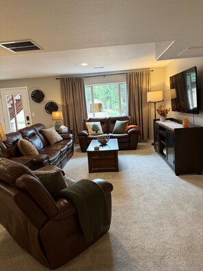 A living room with a brown leather sofa, a wooden coffee table, and a television on a stand. - Summitview Chalet - Mountain Views & CO Charm (Woodland Park)