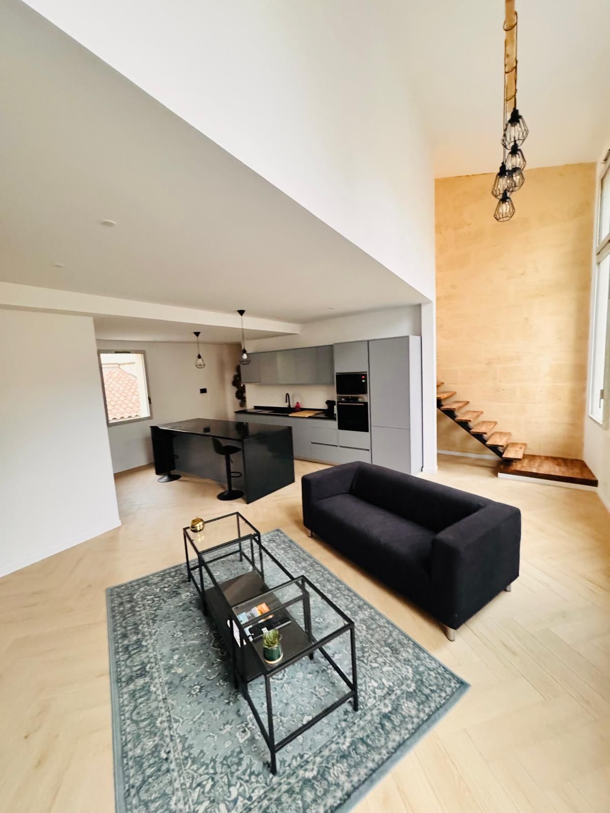 A modern living space with a sofa, coffee table, and a staircase leading to an upper level.