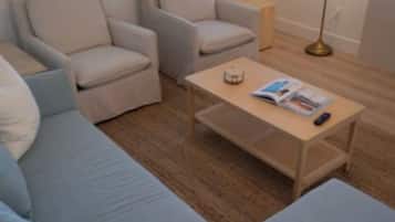 Una habitación con un sofá, sillones, una mesita de centro y una lámpara.